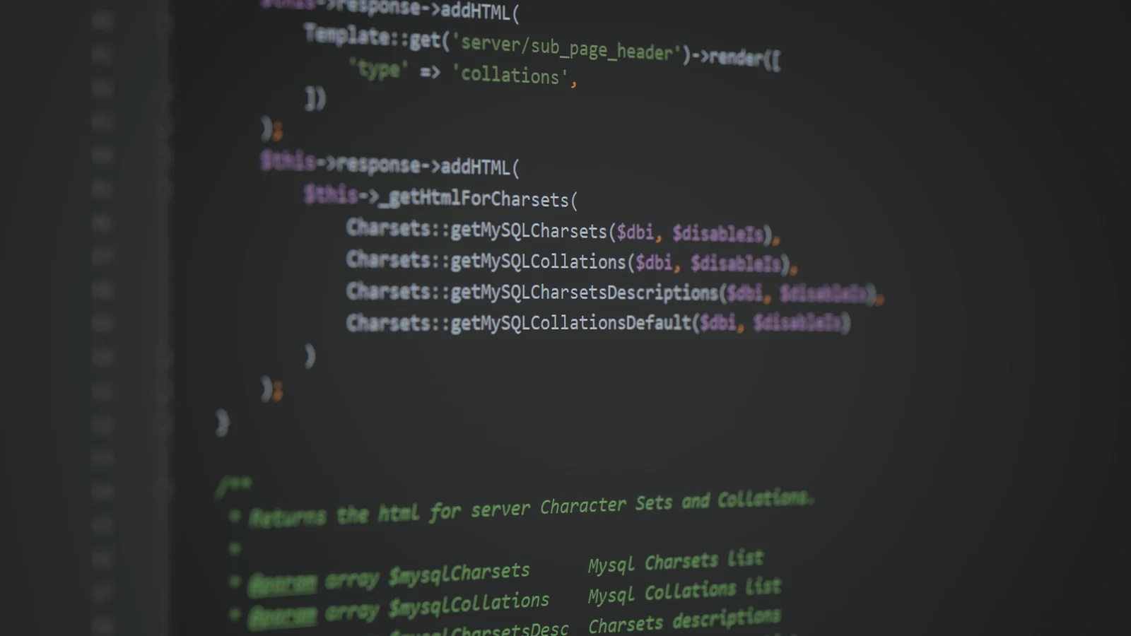A close-up of a computer screen displaying blurred, syntax-highlighted programming code on a dark background.