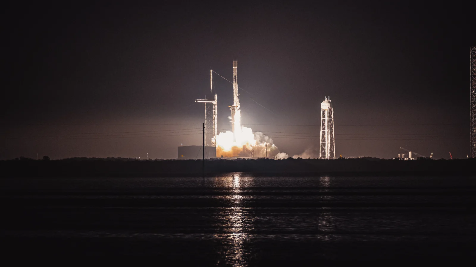 A SpaceX Falcon 9 rocket carrying Starlink satellites launches at night from Kennedy Space Center.